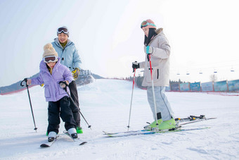 滑雪场上教女儿滑雪的一家三口温馨清晰场景