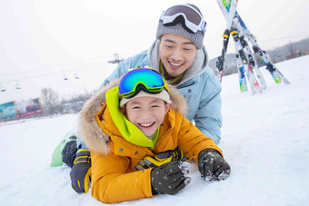 滑雪场内抱在一起打滚的快乐父子东方人高清素材