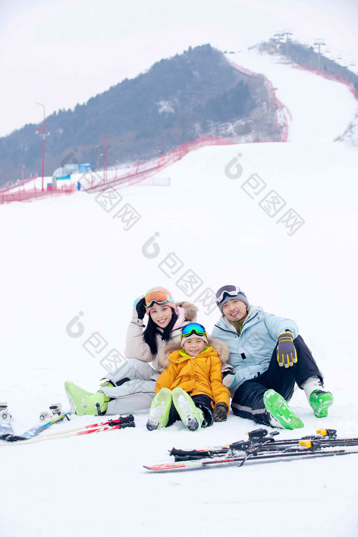 雪场上坐在雪道上的三口之家童年高质量相片