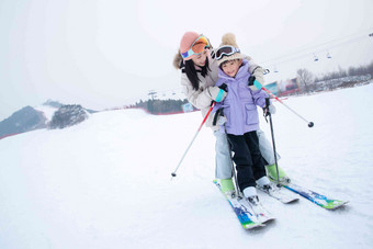 滑雪场上抱在一起滑雪的幸福母女滑高质量图片