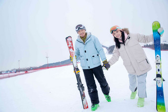 青年伴侣手牵手扶着<strong>滑雪</strong>板站在雪地上