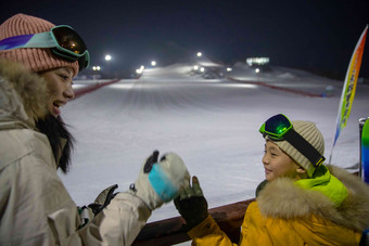 夜幕下雪场上的快乐母子护栏高清相片