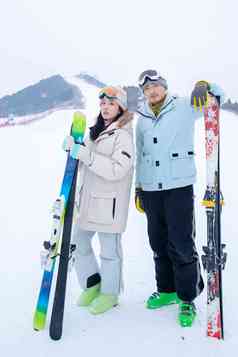 青年伴侣扶着滑雪板站在雪地上