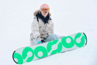 踩着单板坐在雪地上的青年女人全身像高质量素材