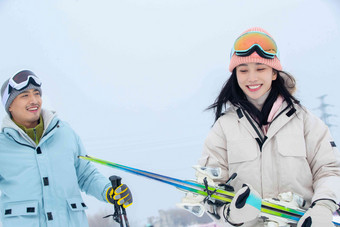 拿着滑雪板滑雪杖的快乐情侣女人拍摄