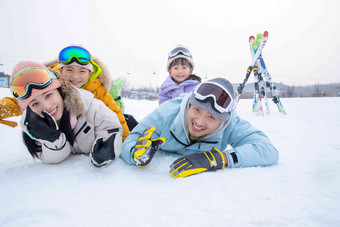 幸福快乐的一家四口趴在雪地上