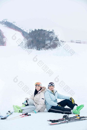 快乐的青年伴侣背靠背坐在雪地上活力高端摄影图