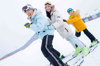 滑雪场上踩着滑雪板排队行走的一家三口成年人高质量摄影