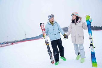 青年伴侣手牵手扶着滑雪板站在雪地上幸福清晰摄影