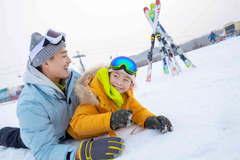 滑雪场内抱在一起打滚的快乐<strong>父子</strong>嬉戏的高清摄影图