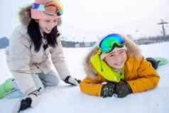 滑雪场内趴在地上打雪仗的快乐母子