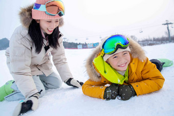 滑雪场内趴在地上打雪仗的快乐母子洒高质量镜头