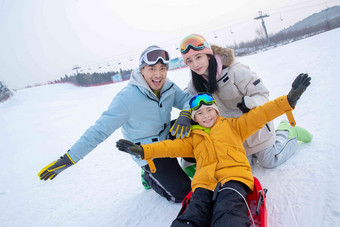 <strong>滑雪</strong>场上父母和坐在雪上滑板的儿子