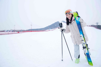 雪场上拿着雪具漂亮的青年女人