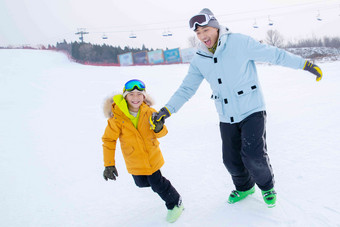 滑雪场内手牵手奔跑的快乐父子两个人清晰相片