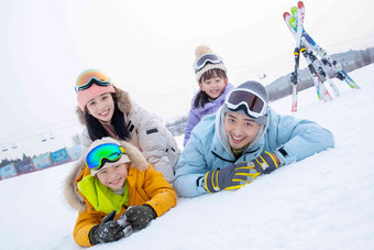 幸福快乐的一家四口趴在雪地上女孩照片