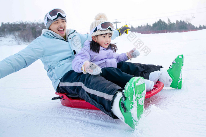 滑雪场上快乐父女坐着雪上滑板滑雪滑雪场高清摄影图