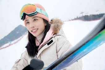 滑雪场上抱着滑雪板漂亮的青年女人乐趣镜头