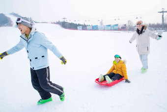 <strong>滑雪</strong>场上父母和坐在雪上滑板的儿子玩耍