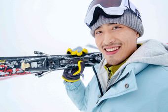 滑雪场上快乐的青年男人扛着滑雪板白昼写实场景