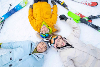 快乐的一家三口放松的躺在雪地上母亲镜头