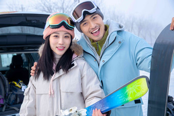 汽车后备箱旁的青年伴侣拿着滑雪板