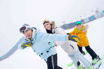 滑雪场上踩着滑雪板排队行走的一家三口滑雪场高端照片