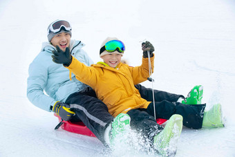 兴奋的父子坐着雪上滑板滑雪