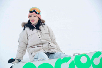 踩着单板坐在雪地上的青年女人笑高端摄影