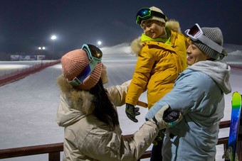 夜景下的滑雪场内的一家三口