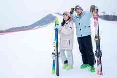 青年伴侣扶着滑雪板站在雪地上