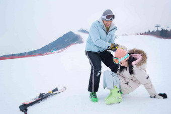 滑雪场上青年男人扶女朋友站起来相伴写实图片