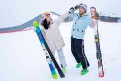 青年伴侣扶着滑雪板在雪地上玩耍