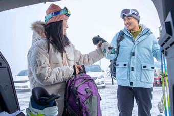 停车场内青年伴侣从汽车后备箱拿雪具娱乐高清素材