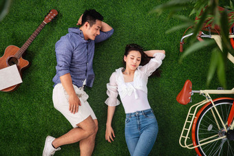 幸福的青年伴侣躺在草地上小憩休息写实相片