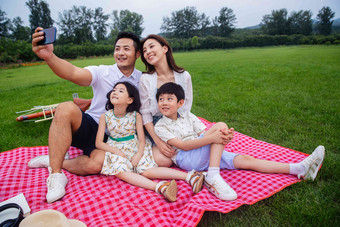 幸福的一家四口坐在野餐垫上自拍