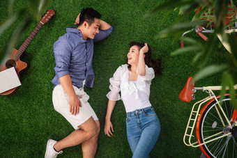 幸福的青年伴侣躺在草地上聊天
