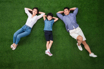 幸福的一家三口躺在草地上白昼氛围相片