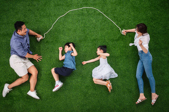 快乐的一家四口在草地上跳绳享乐高质量相片