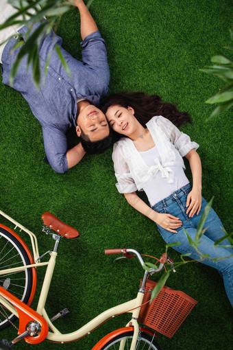 甜蜜的青年伴侣躺在草地上