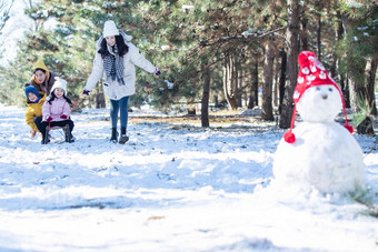 在雪地上玩雪橇的一家人儿子写实相片