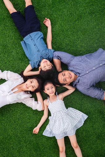 幸福的一家四口头挨着头躺在草地上两个孩子的家庭高端素材