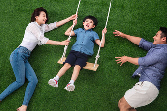 幸福的三口之家在草地上荡秋千儿子高端图片