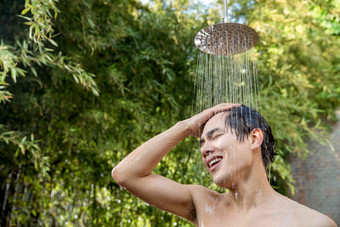 年轻男人在户外淋浴洗头
