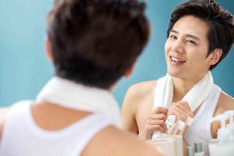 快乐的年轻男人拿着毛巾照镜子欣赏高质量照片