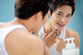 青年男人对着镜子刮胡子彩色图片高端相片