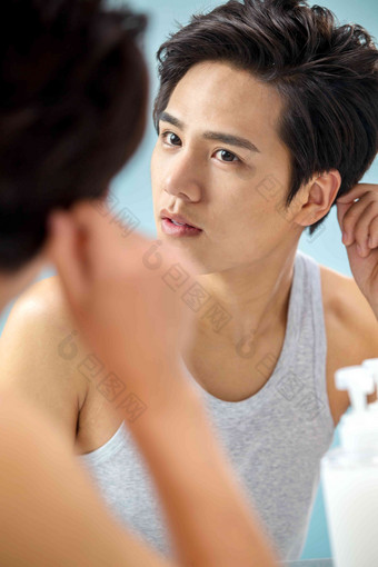 照着镜子整理发型的年轻男人