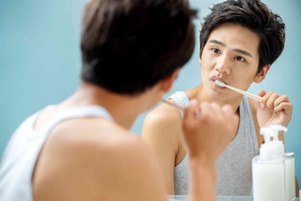 年轻男人对着镜子在刷牙年轻人高清摄影