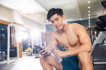 青年男人在健身房里喝水健身俱乐部高质量摄影