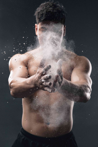 举重运动员往手上涂抹滑石粉拍手高质量摄影